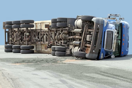 Large blue semi-truck lays on its side on the road after a crash
