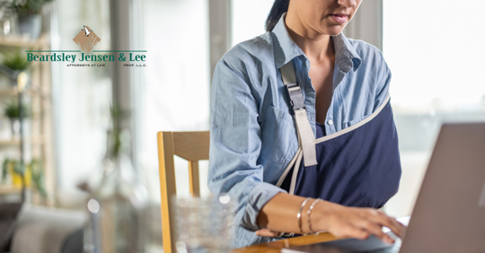Woman with arm sling using laptop after burn injury